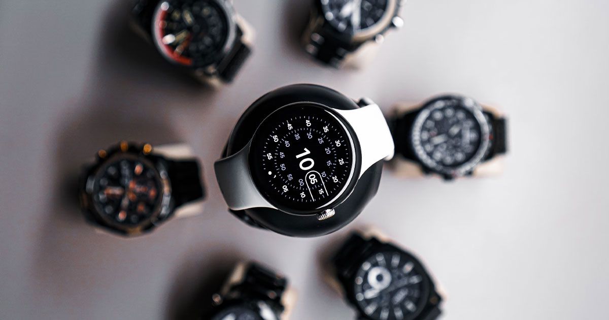 A white-strapped smartwatch on a plinth surrounded by other watches.